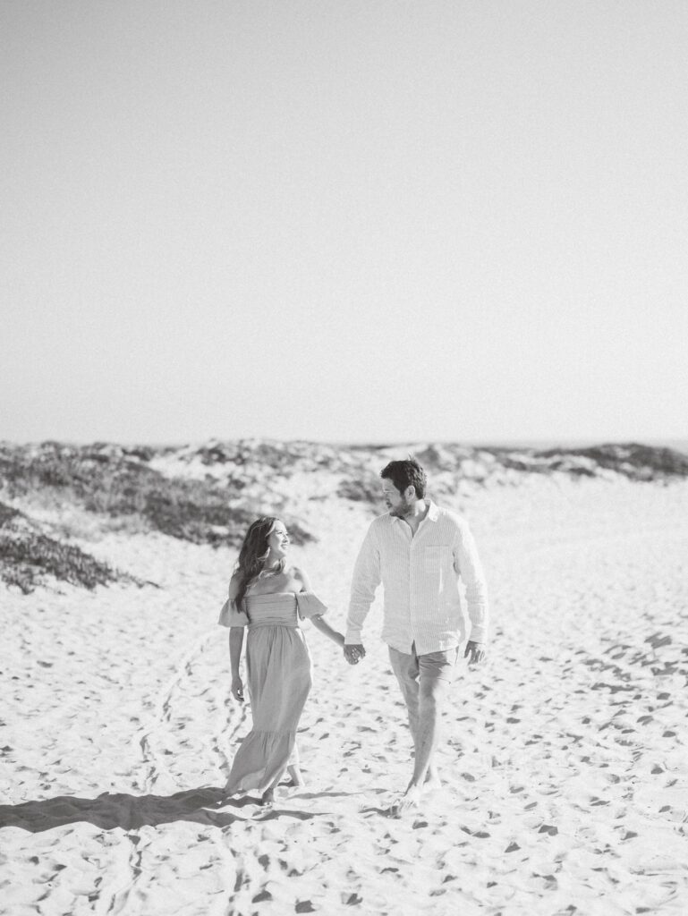 a man and woman holding hands on a Coronado sand dunes